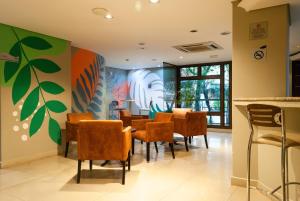 庫里奇巴的住宿－Master Curitiba Hotel - 1,6 km do Estádio Couto Pereira - Show，用餐室配有椅子和墙上的绘画作品