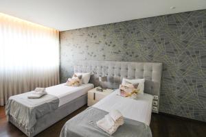 ヴィラ・ノヴァ・デ・ガイアにあるOcean View Luxury Apartmentのベッドルーム1室(ベッド2台付)が備わります。壁に壁画が飾られています。