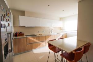 Una cocina con gabinetes blancos y una mesa y sillas. en Ocean View Luxury Apartment, en Vila Nova de Gaia