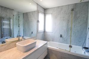 La salle de bains est pourvue d'un lavabo, d'une baignoire et d'un miroir. dans l'établissement Ocean View Luxury Apartment, à Vila Nova de Gaia