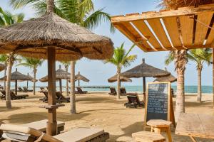 - une plage avec des chaises et des parasols et l'océan dans l'établissement Neptune, à Saly Portudal