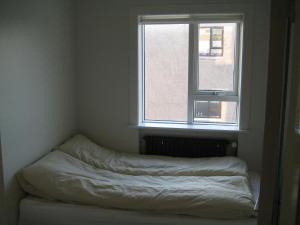 an unmade bed in a room with a window at Central Reykjavík Apartment in Reykjavík