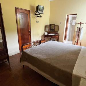 a bedroom with a bed and a tv on the wall at Hotel Bragança in Caxambu