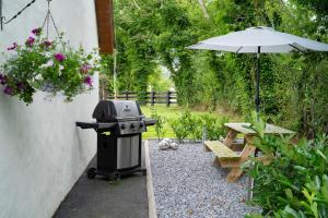 a grill and a picnic table with an umbrella at Cherry Tree Apartment in Artikelly