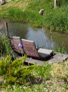 two wicker chairs sitting next to a river at Les Gîtes de L'Yères in Cuverville-sur-Yères