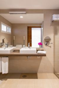 a bathroom with two sinks and a large mirror at Parador de Mazagón in Mazagón