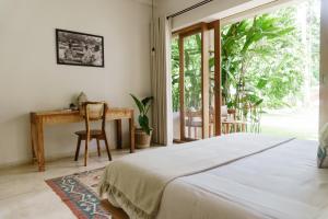 a bedroom with a bed and a desk and a window at The Nook RESORT in Devinuwara