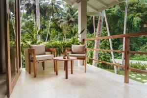 a porch with chairs and a table and trees at The Nook RESORT in Devinuwara