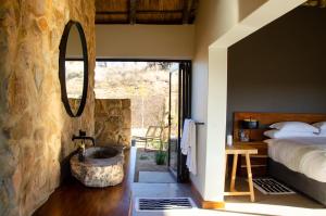a bedroom with a bed and a stone wall at Sibani Lodge in Krugersdorp