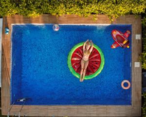 a woman is laying on a slice of tomato in a swimming pool at Corinthian Village in Vrachati