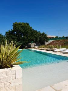 einen Pool mit blauem Wasser, Stühlen und Bäumen in der Unterkunft Lamacesare in Cisternino