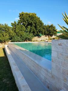 a stone retaining wall next to a swimming pool at Lamacesare in Cisternino