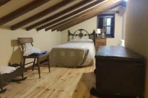 a bedroom with a bed and a desk and a chair at Cabaña Pasiega "La Reina del Paraíso" in San Roque de Ríomiera