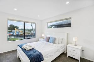 a white bedroom with a bed and a window at Modern Family Townhouse in Mt Roskill, Auckland in Auckland