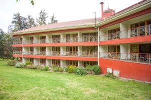 un bâtiment rouge avec une cour verdoyante devant lui dans l'établissement Hotel y Cabañas Palomar - Caja los Andes, à San Felipe