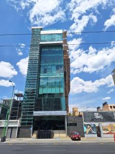 a tall glass building with a car in front of it at Increible SUITE A con vista a la Ciudad in Mexico City