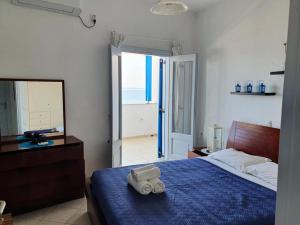 a bedroom with a bed with a blue blanket and a mirror at Rodothea and Adams on the Beach, Santorini in Monolithos