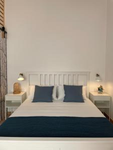 1 dormitorio con 1 cama blanca grande con almohadas azules en A'mmare Rooms&Apartments Santa Maria di Leuca en Leuca