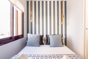 ein Schlafzimmer mit einem Bett mit Kissen und einer gestreiften Wand in der Unterkunft Apartamento Torremolinos centro in Torremolinos