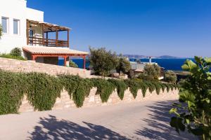 una casa con una pared de piedra y un camino de entrada en Alexena Apartments en Agia Galini