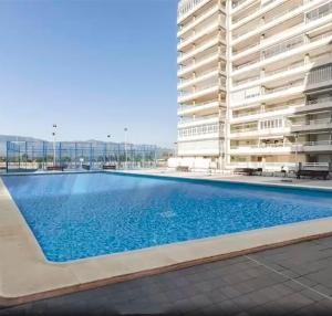 a swimming pool in front of a building at Apartamento en urbanización lujo in Tavernes de Valldigna