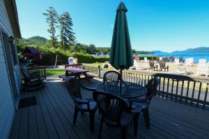 una terraza con mesa, sillas y sombrilla en Lake George Diamond Cove Cottages, Cabins, & Hotel, en Lake George