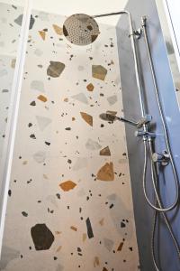 a bathroom with a shower with a wall covered in rocks at Mimosa e Agave Blu in Scicli