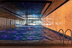 uma piscina num edifício com uma pessoa a nadar nela em Royal Waves Resort & SPA - Apartment with Parking by Renters em Międzyzdroje