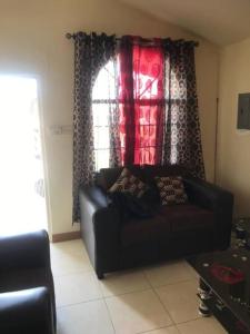 a living room with a black couch in front of a window at Leila VIllage Plus in Mendes