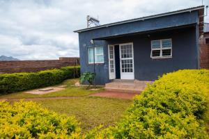 una casa azul con una puerta blanca y algunos arbustos en 2 bedroom modern house in Zomba, en Zomba