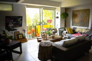 a living room with a couch and a large window at Pequeña habitacion FRIDA - design CDMX - áreas comunes compartidas in Mexico City