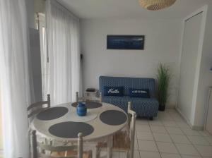a table and chairs in a living room with a couch at L'Albatros 15 in Fort-Mahon-Plage