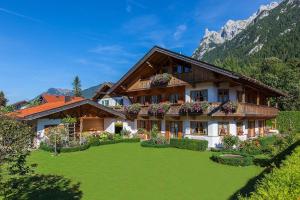 a house in the mountains with a green yard at Ferienhaus Alpenblick in Mittenwald