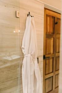 a white robe hanging on a rack in a bathroom at Hotel Apapacho Boutique in San Miguel de Allende