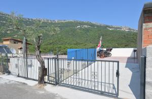 a gate in a parking lot with a motorcycle behind it at Eliseo's rooms in Triei