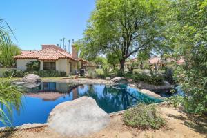 a yard with a pond in front of a house at Palm Desert Condo Country Club Perks and Pond Views in Palm Desert