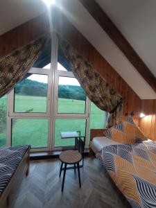 a bedroom with two beds and a large window at Domek Bieszczadzki Horyzont in Berezka