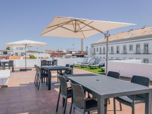 a patio with tables and chairs and an umbrella at Dear Faro - Guest House in Faro