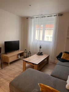uma sala de estar com uma televisão de ecrã plano e uma mesa em Appartement 1 au cœur de Périgueux em Périgueux