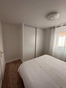 um quarto com uma cama branca e uma janela em Appartement 1 au cœur de Périgueux em Périgueux