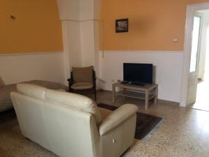 een woonkamer met een witte bank en een televisie bij La Casetta di Angela in Manduria