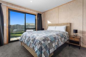 a bedroom with a bed and a large window at Beach Bach on Boulevard in Opotiki