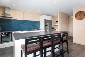 a kitchen with a counter with stools in it at Beach Bach on Boulevard in Opotiki