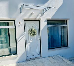 een wit huis met een deur met een krans erop bij Sweet Home - Praia das Rocas in Castanheira de Pêra