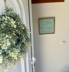 uma coroa de flores numa porta com uma fotografia na parede em Sweet Home - Praia das Rocas em Castanheira de Pêra