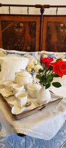 een tafel met witte gerechten en een vaas met rozen bij La Casa del Borgo Antico in Spoleto