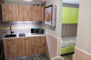 a small kitchen with wooden cabinets and a microwave at Appartamenti Vale Mare 2 in Chioggia