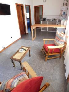 a living room with chairs and tables and a kitchen at CABAÑAS LOS COIRONES in El Calafate