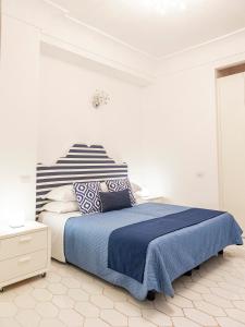 una camera bianca con letto con lenzuola e cuscini blu di Villa Nannina a Positano