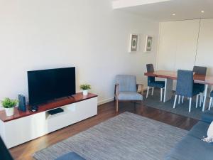 een woonkamer met een flatscreen-tv en een tafel bij Casa do Cinema in Nazaré